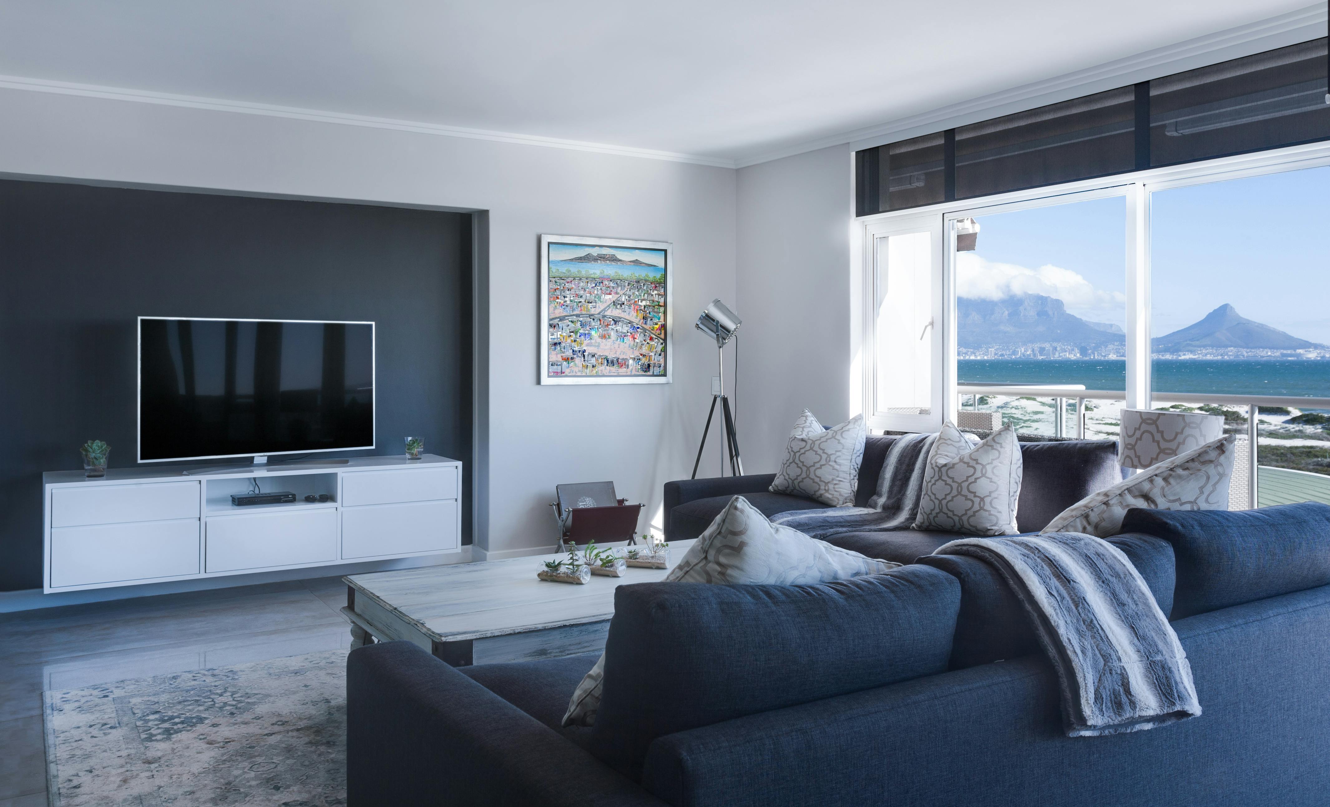 A relaxed living room with a deep sofa, soft textiles, and ocean light